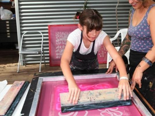 Audrey Bush using squeegy to make sceenprint with Joanna Kambourian looking on