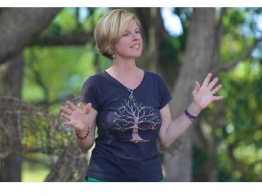 woman talking in front of tree with hands raised