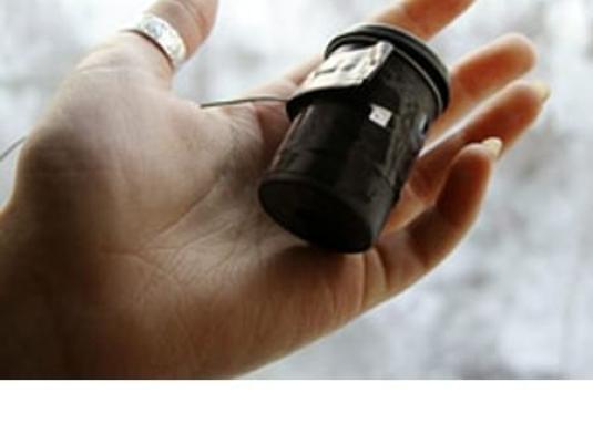 a hand with ring on the thumb with a film roll canister in the palm of hand