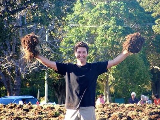 man holding clumps of soil and grass