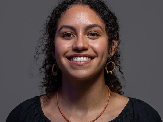 A portrait of a young First Nations Papua woman against a grey backdrop