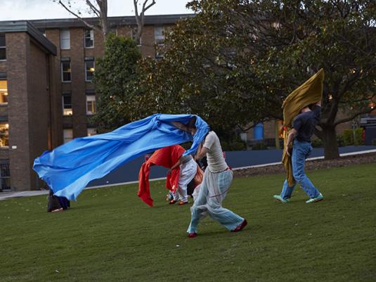 People in a park moving with large colourful fabric banners