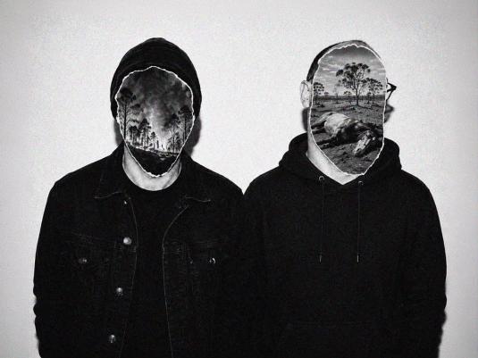 A black and white photo of two people wearing black hoodies against a white wall. Where their faces should be is a cut out photo of a landscape